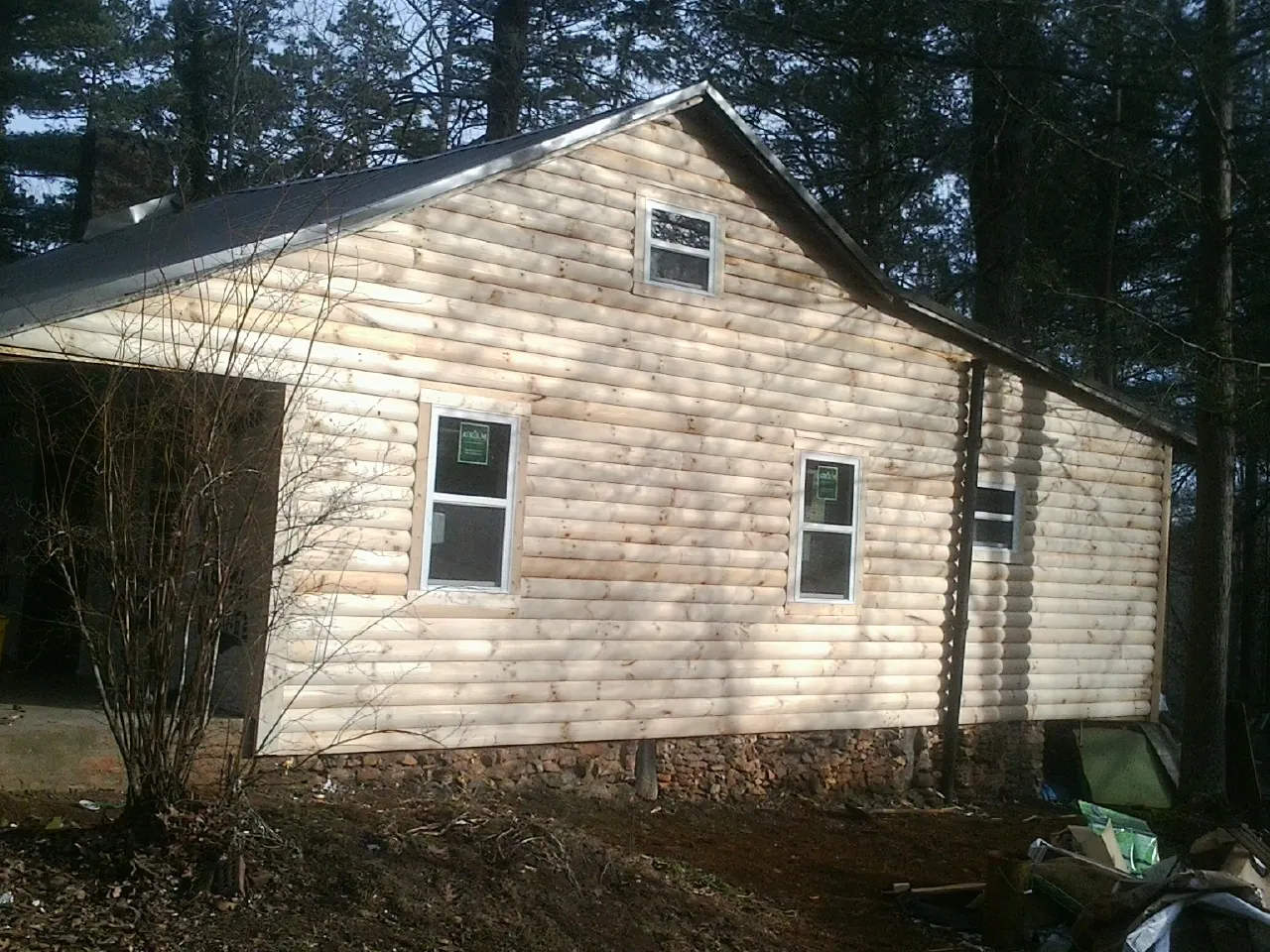 New log siding and dark metal roofing on a gable end in Evadale