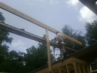 Carpenter setting a ridge beam over a new addition frame — Ice Dam Removal by Roofing Brothers in Evadale