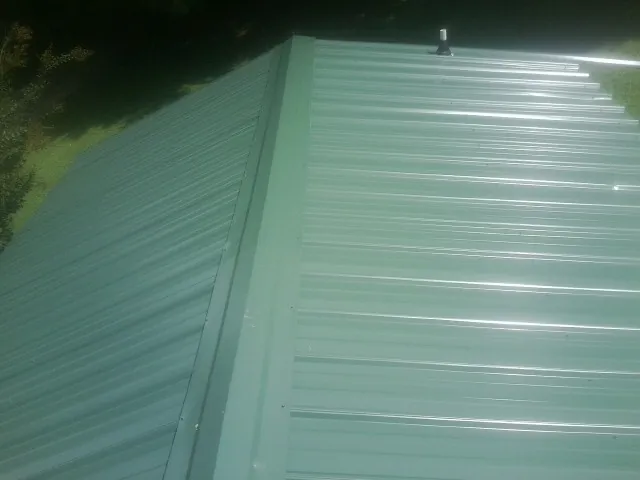 New green metal panels meeting at the ridge of a roof — Flat Roof Repair work by our crew in Evadale