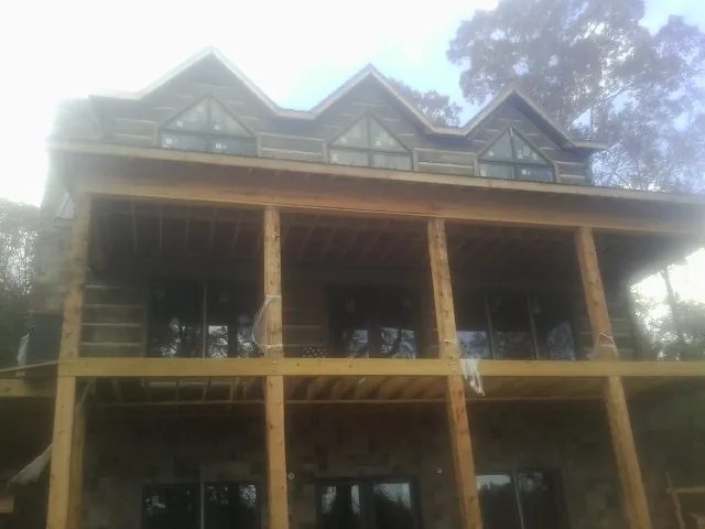 Dormers and porch framing on a large log home under construction — Roof Coating work by our crew in Evadale