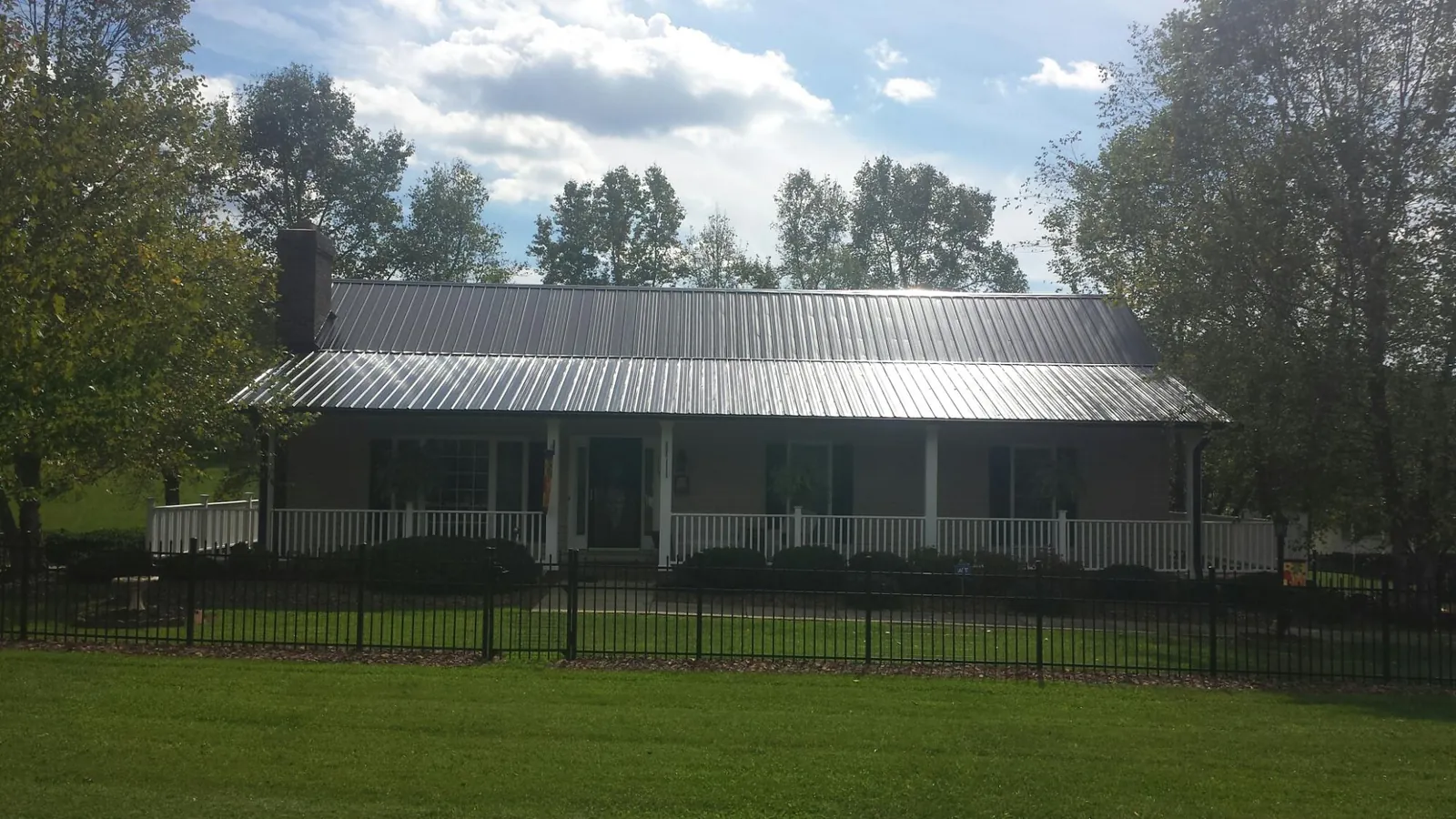 Gray metal roof on a brick ranch with a full width front porch — Gutter Guard Installation work by our crew in Evadale