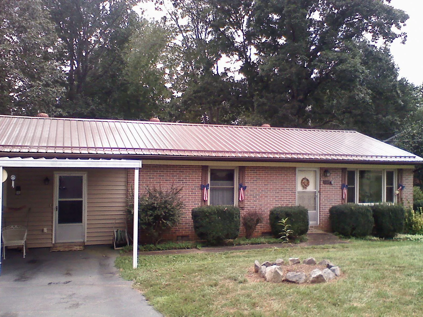 Bronze metal roof and carport on a brick ranch home — Roof Repair work by our crew in Evadale